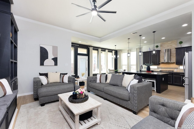 living room with crown molding, ceiling fan, sink, and light hardwood / wood-style floors