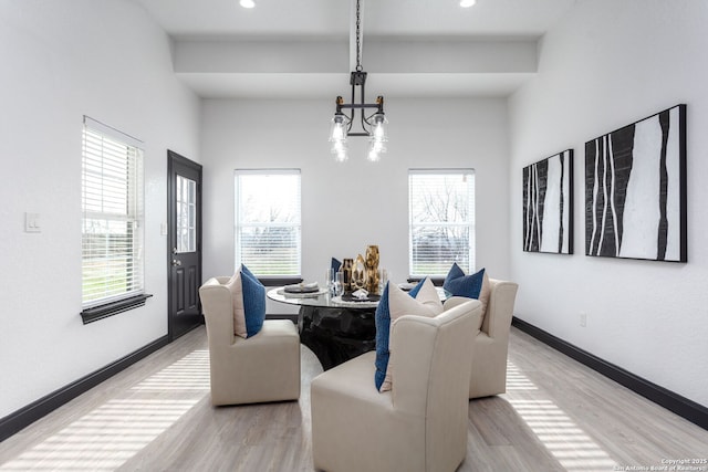 dining room with light wood-type flooring, a wealth of natural light, and a chandelier