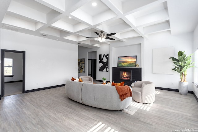 living room featuring ceiling fan, beam ceiling, coffered ceiling, a brick fireplace, and light wood-type flooring