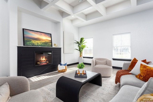 living room featuring coffered ceiling, light hardwood / wood-style floors, beamed ceiling, and a high ceiling