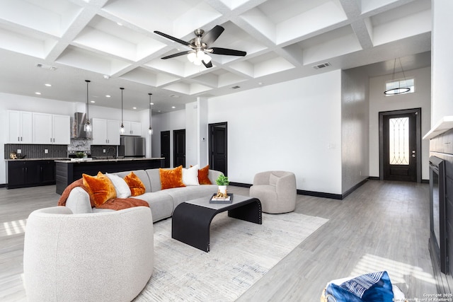 living room with a towering ceiling, coffered ceiling, sink, and beam ceiling