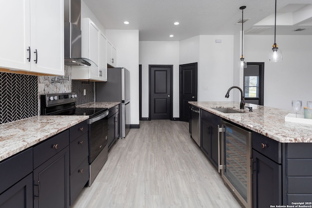 kitchen featuring sink, appliances with stainless steel finishes, white cabinetry, wine cooler, and wall chimney exhaust hood