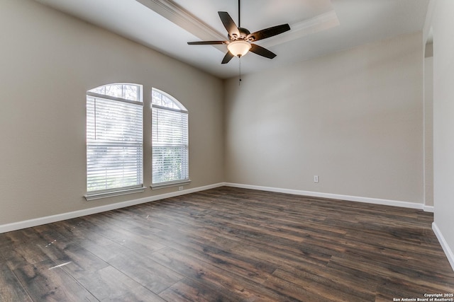 empty room featuring dark hardwood / wood-style floors, ceiling fan, and a raised ceiling