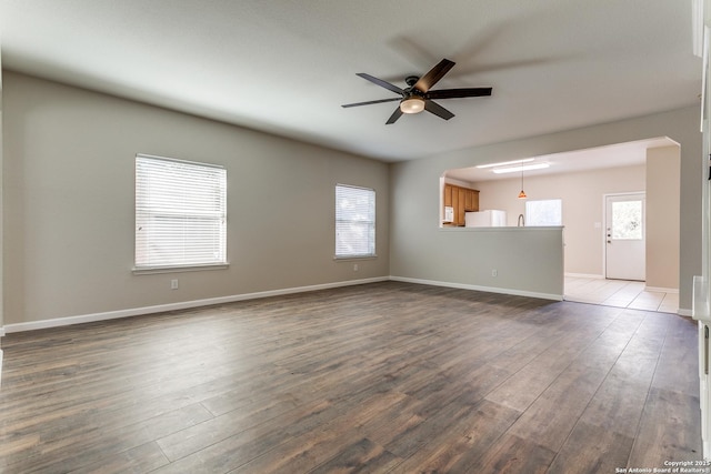 unfurnished living room with ceiling fan, a wealth of natural light, and wood-type flooring