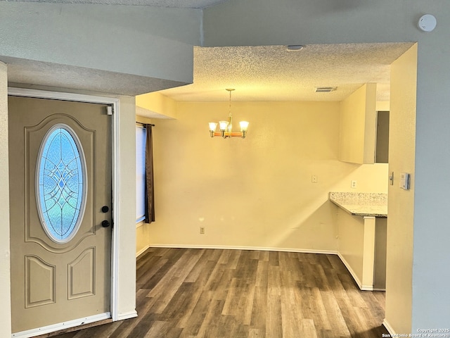 foyer with an inviting chandelier, wood-type flooring, and a textured ceiling