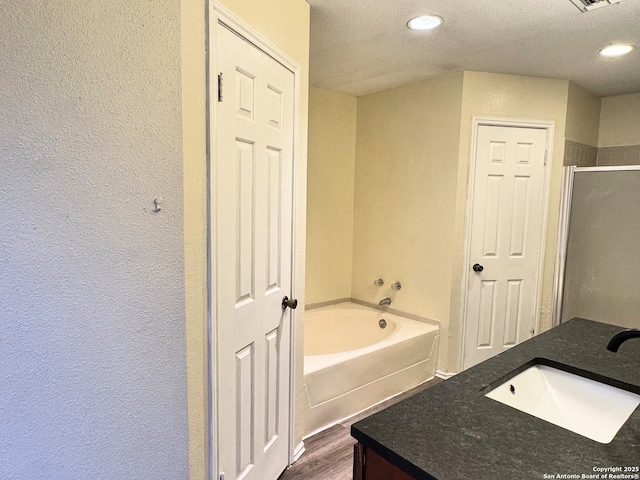 bathroom featuring vanity, hardwood / wood-style flooring, shower with separate bathtub, and a textured ceiling