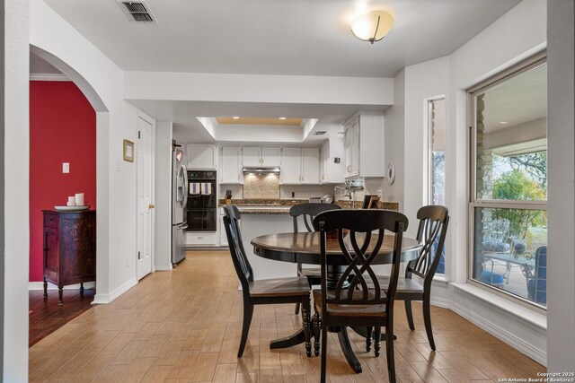 dining room with light hardwood / wood-style floors and a raised ceiling