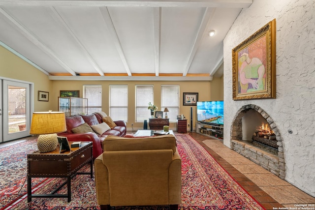 living room featuring plenty of natural light, a stone fireplace, and lofted ceiling with beams