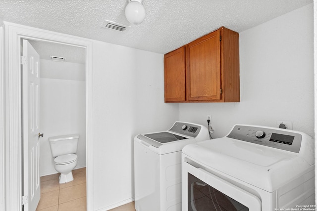 25002 Silverstone, San Antonio, TX 78258 - washroom featuring washer and clothes dryer, cabinet space, light tile patterned flooring, and a textured ceiling