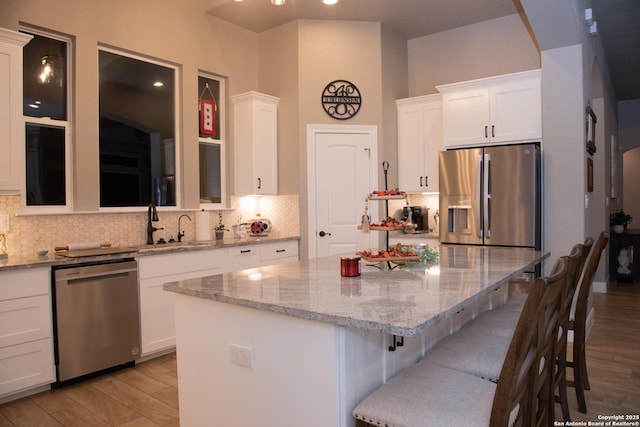 kitchen with white cabinetry, appliances with stainless steel finishes, a breakfast bar, and a kitchen island