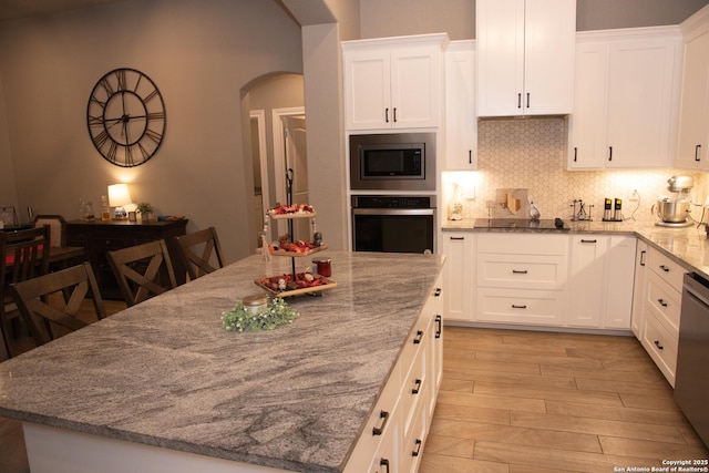 kitchen featuring white cabinets, decorative backsplash, light hardwood / wood-style floors, stainless steel appliances, and light stone countertops