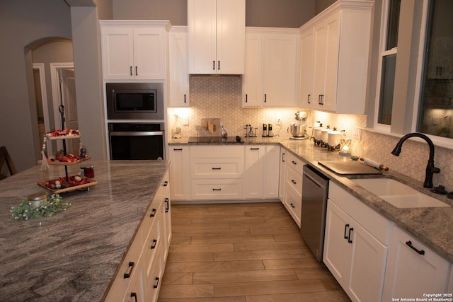 kitchen featuring light stone counters, sink, stainless steel appliances, and white cabinets