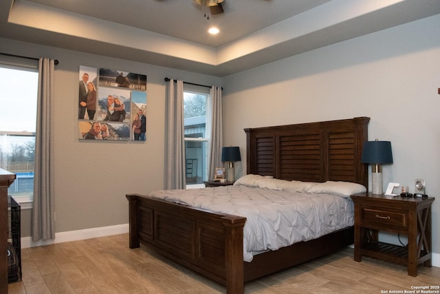 bedroom with a raised ceiling and light wood-type flooring