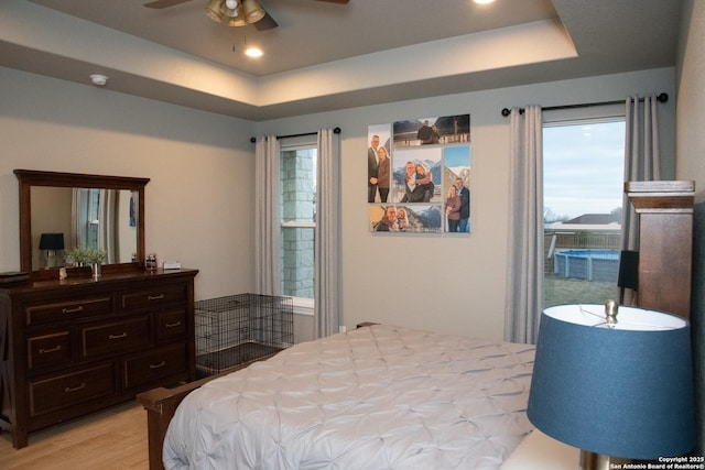 bedroom with a raised ceiling and light wood-type flooring