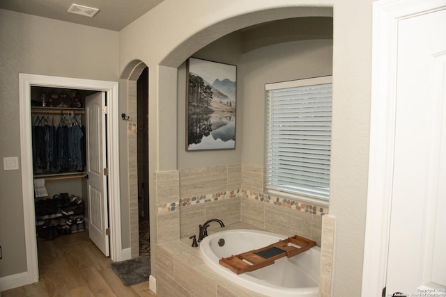 bathroom with hardwood / wood-style flooring and tiled bath