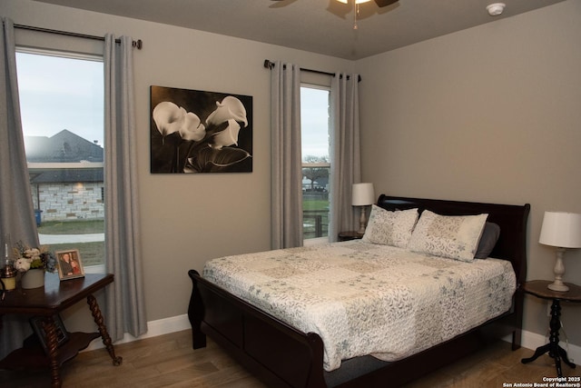 bedroom with hardwood / wood-style flooring, ceiling fan, and multiple windows