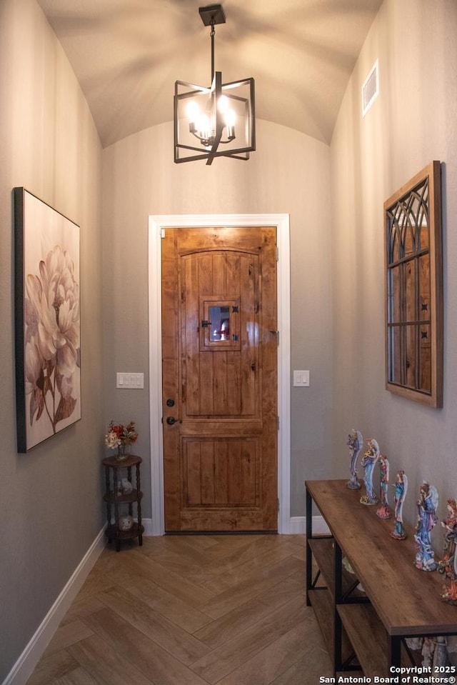 foyer with lofted ceiling, hardwood / wood-style floors, and a chandelier