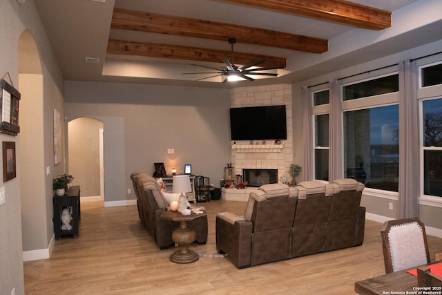 living room with beam ceiling, a fireplace, light hardwood / wood-style floors, and ceiling fan