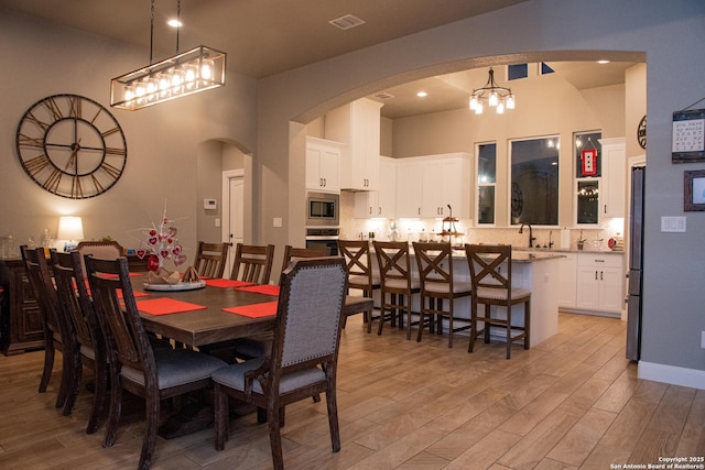 dining space with a towering ceiling and light hardwood / wood-style flooring