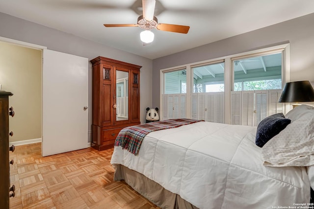 bedroom with ceiling fan, multiple windows, and light parquet floors