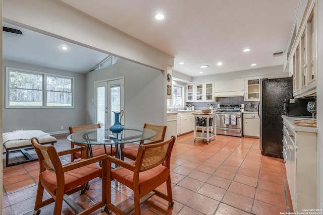 tiled dining room featuring lofted ceiling and french doors