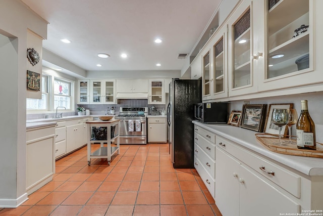 kitchen with sink, light tile patterned floors, stainless steel appliances, decorative backsplash, and white cabinets