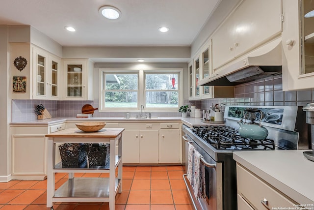 kitchen with sink, tasteful backsplash, white cabinets, light tile patterned flooring, and stainless steel range with gas cooktop