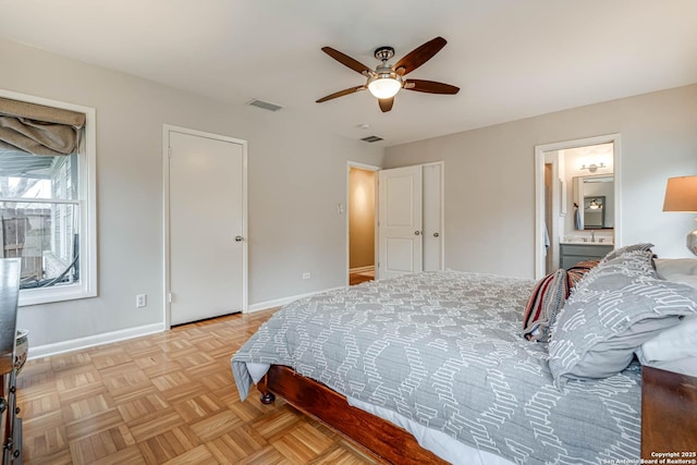 bedroom with light parquet floors, connected bathroom, and ceiling fan