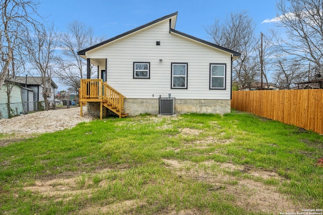 rear view of property with cooling unit and a lawn