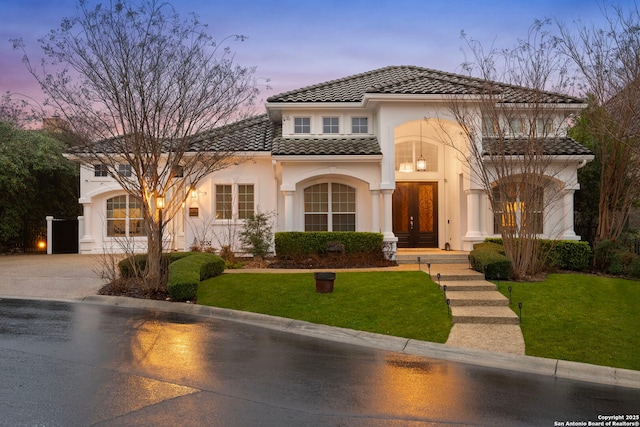 mediterranean / spanish house featuring french doors and a lawn