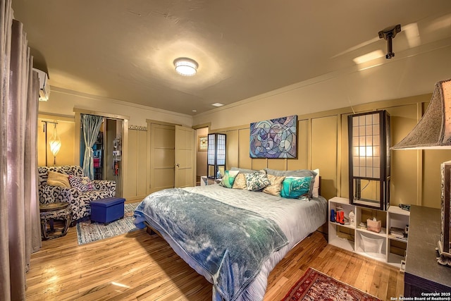 bedroom with ornamental molding and light hardwood / wood-style floors