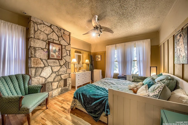 bedroom featuring ceiling fan, a textured ceiling, and light wood-type flooring