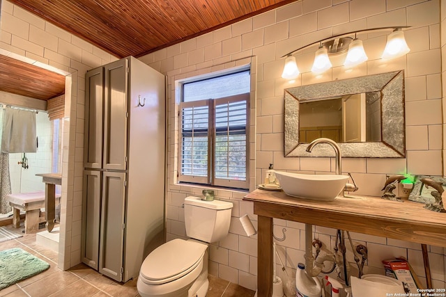 bathroom with tile patterned flooring, sink, tile walls, and wood ceiling