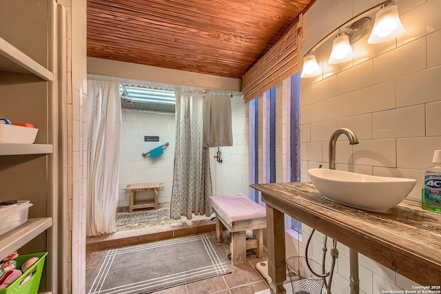 bathroom featuring tile patterned floors, sink, tile walls, wooden ceiling, and curtained shower