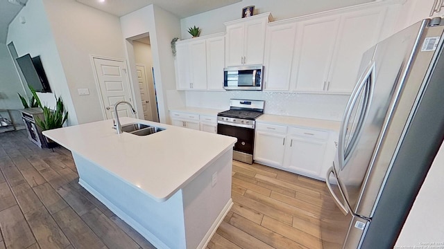 kitchen featuring white cabinetry, stainless steel appliances, sink, and a center island with sink