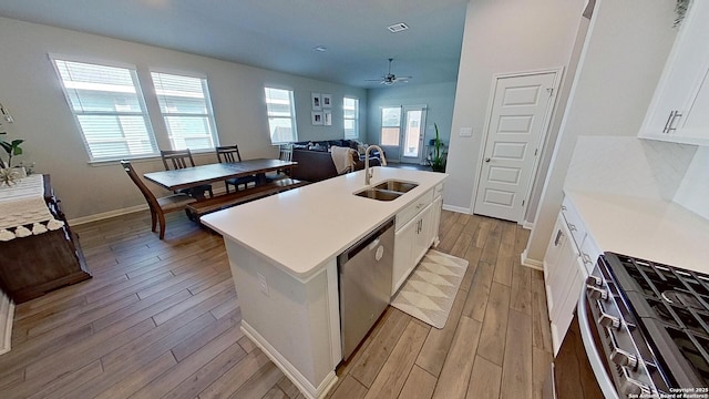 kitchen with sink, white cabinets, a kitchen island with sink, light hardwood / wood-style floors, and stainless steel appliances