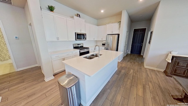 kitchen featuring sink, light hardwood / wood-style flooring, appliances with stainless steel finishes, a kitchen island with sink, and white cabinets