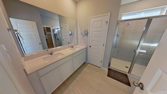 bathroom with a shower with door, vanity, and tile patterned floors