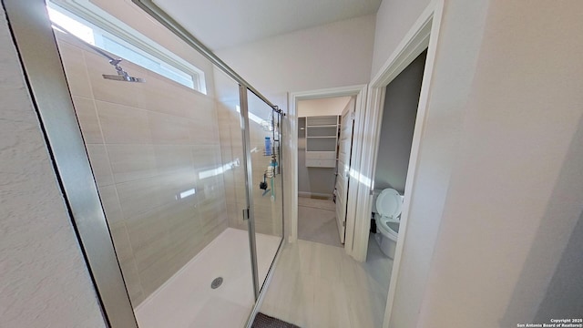 bathroom featuring toilet and a shower with shower door