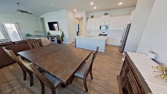 dining room with ceiling fan, sink, and light hardwood / wood-style floors