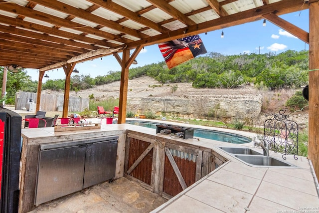 view of patio featuring a fenced in pool, exterior kitchen, and a wet bar