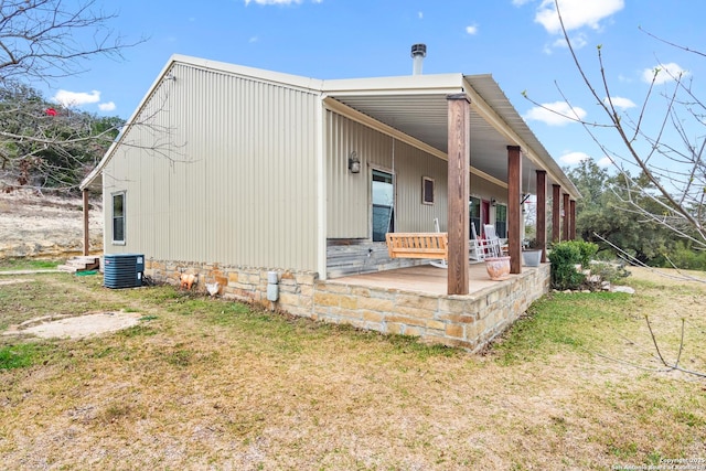 view of property exterior with central AC, a porch, and a lawn