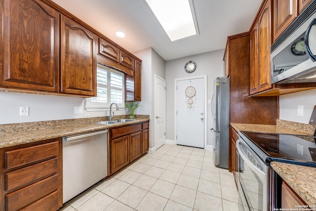 kitchen featuring sink, light tile patterned flooring, stainless steel appliances, and light stone countertops