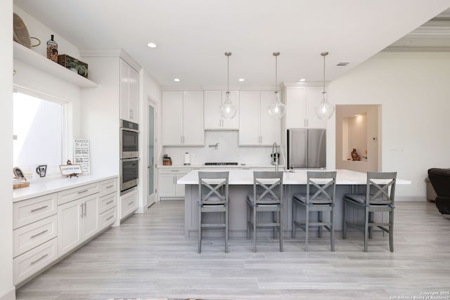 kitchen with pendant lighting, a breakfast bar area, white cabinetry, stainless steel appliances, and a spacious island