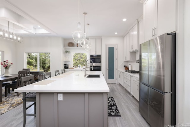 kitchen featuring appliances with stainless steel finishes, white cabinetry, sink, a kitchen bar, and a spacious island