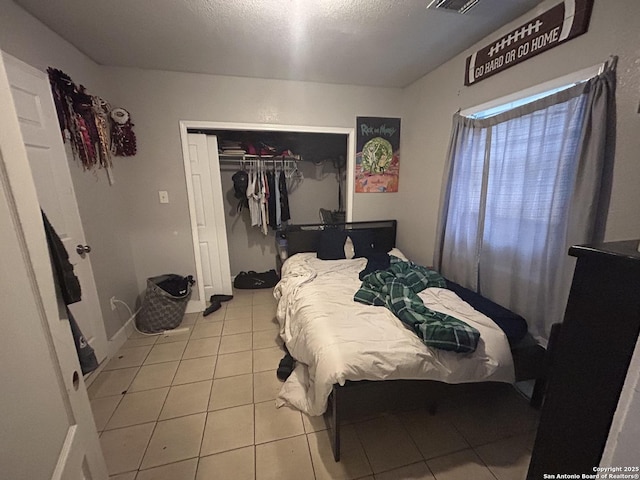 bedroom with light tile patterned floors, a closet, and a textured ceiling