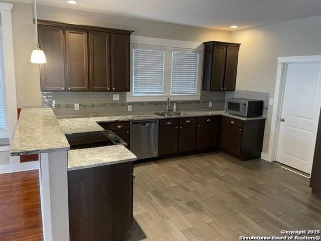 kitchen featuring a breakfast bar, sink, stainless steel dishwasher, kitchen peninsula, and pendant lighting