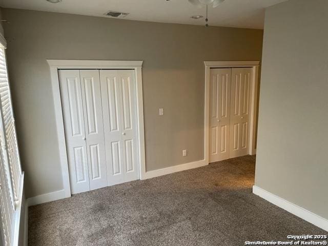 unfurnished bedroom featuring carpet flooring and two closets