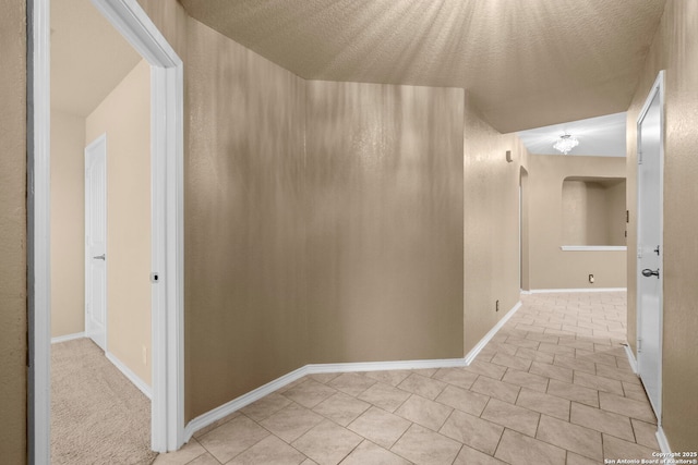 hall with light tile patterned floors and a textured ceiling