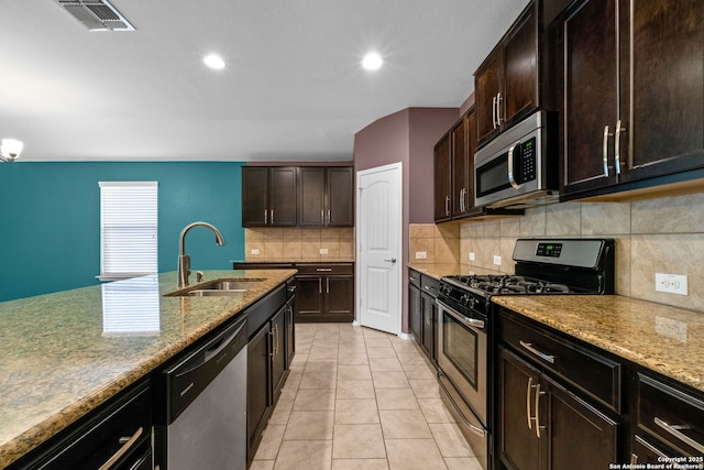 kitchen featuring appliances with stainless steel finishes, tasteful backsplash, sink, light stone countertops, and dark brown cabinets